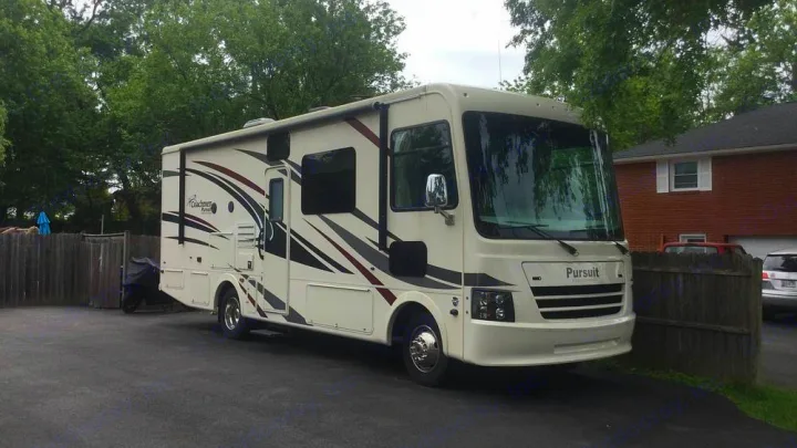 Large white Coachmen Pursuit Class A RV rental, with red/dark graphics, parked on a paved driveway.. Coachmen Pursuit 27DS 2019