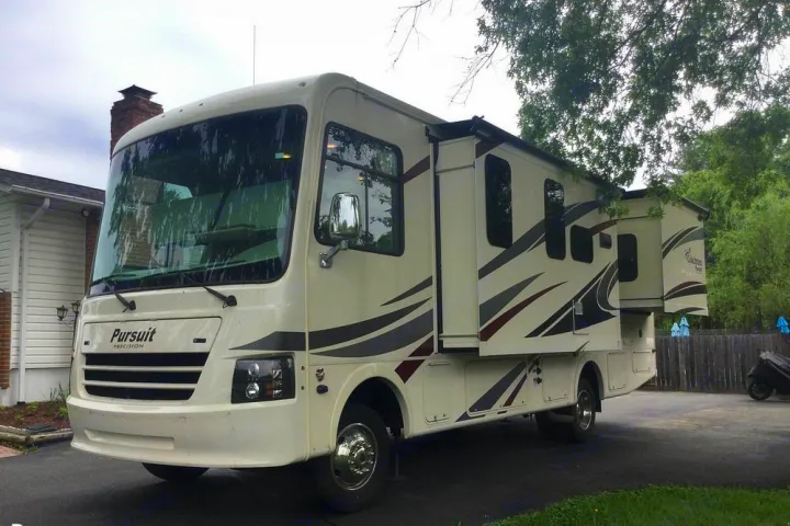 This cream-colored Class A RV, with slide-outs extended, is available for your next rv rental adventure.. Coachmen Pursuit 27DS 2019