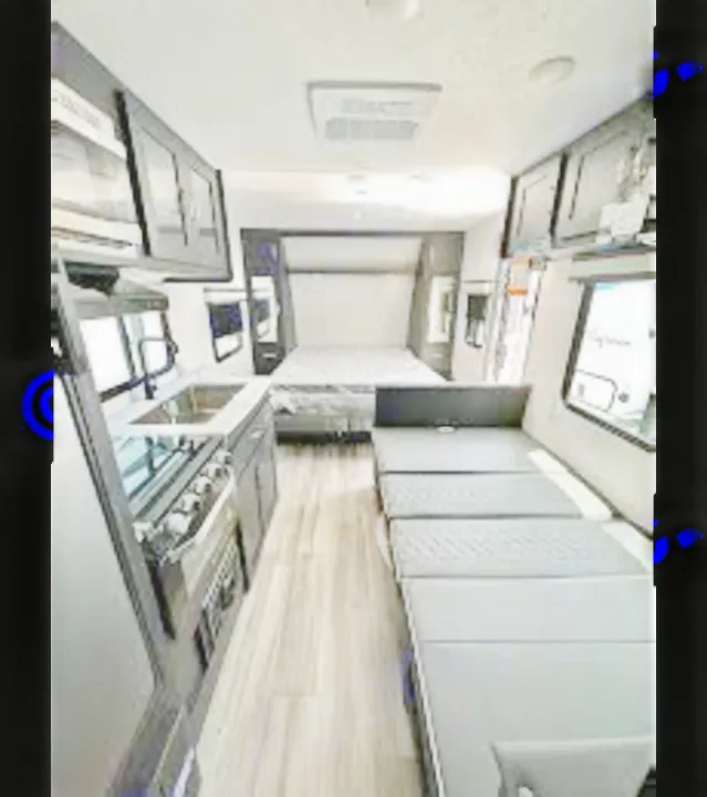 Explore this compact RV rental interior! Features a sleek kitchenette, convertible lounge, and cozy bedroom. Perfect for your next road trip.. Coachmen Freedom Express 2023