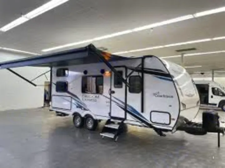 This white travel trailer RV rental, with an extended awning and steps down, is ready for your next adventure.. Coachmen Freedom Express 2023
