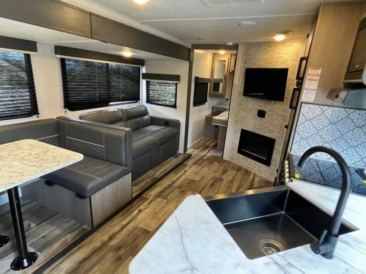 Modern RV rental: spacious camper interior with dinette, sofa, kitchen, TV, & fireplace for comfortable travel.. Dutchmen Coleman Light 2022
