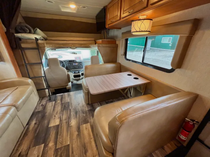 Interior view of an rv rental featuring a dinette, sofa, overhead bunk, and wood plank flooring.. Nexus Phantom 32P 2019