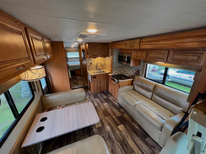 Inside this cozy RV rental: a well-equipped kitchen, dinette, sofa, and view to the bedroom. Ready for your trip!. Nexus Phantom 32P 2019