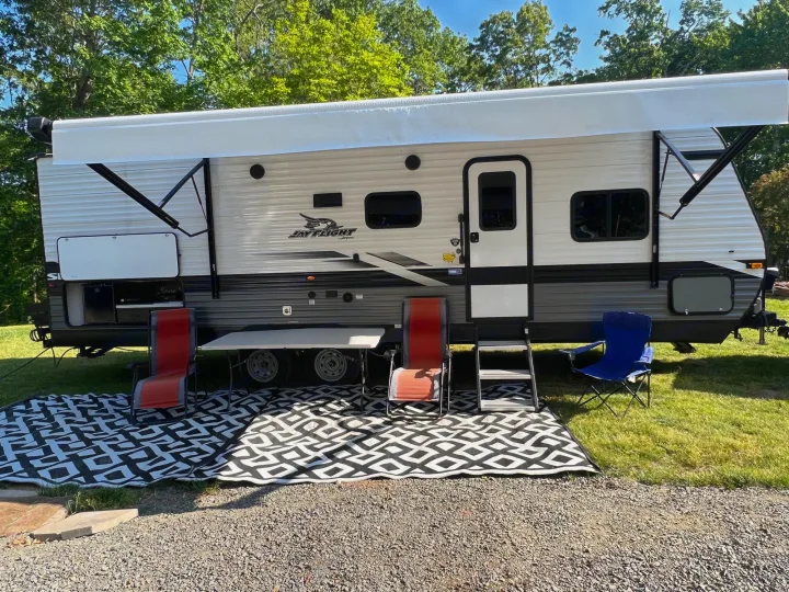 Spacious Jay Flight travel trailer RV rental with extended awning, outdoor mat, table, and chairs for camping.. Jayco Jay Flight SLX 2022