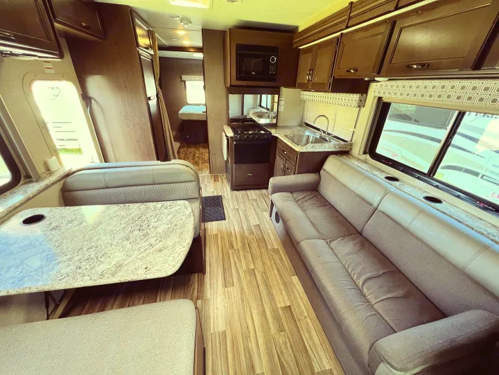 Spacious RV rental interior featuring a dinette, sofa, kitchen, and rear bedroom. Perfect motorhome for your travels.. Thor Motor Coach Four Winds 2019