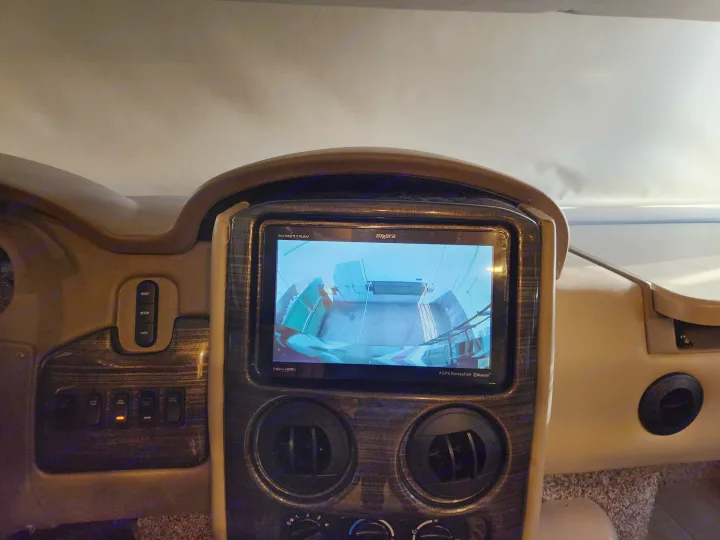 RV rental dashboard: Central screen shows rearview camera feed. Navigation and control panel visible, generator start light illuminated.. Thor Challenger 2019