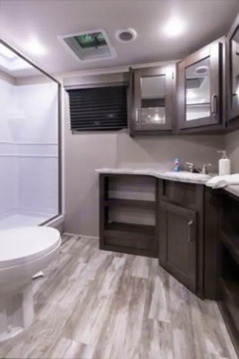 Spacious RV rental bathroom featuring a shower, toilet, and vanity with ample storage. Modern interior design for comfort.. Grand Design transcend 2021
