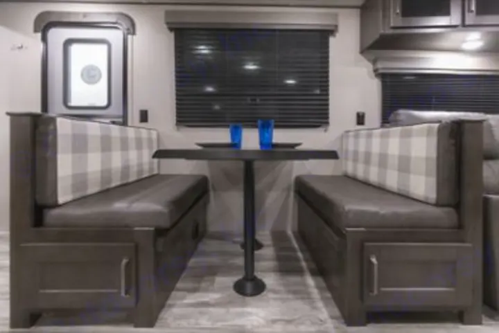 This inviting RV rental dinette with plaid seating and a table offers comfortable travel accommodations.. Grand Design transcend 2021
