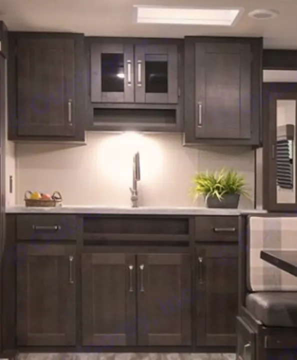 RV rental interior: A dark wood kitchen with sleek sink, under-cabinet lighting, and cozy dinette, ready for travel.. Grand Design transcend 2021