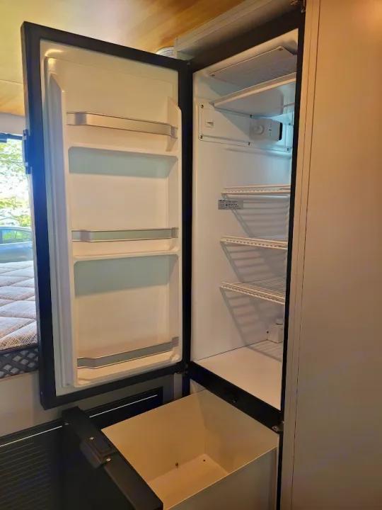 Explore this empty RV rental refrigerator, featuring clean shelves, door storage, and a handy lower bin.. Promaster 3500 EXT 2022