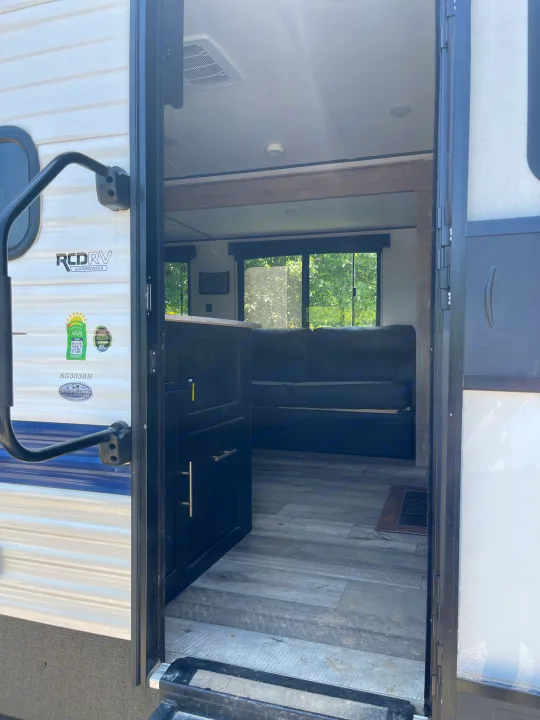 Open door view of an RV rental interior: grey flooring, dark cabinets, and a comfy couch. Perfect for your next adventure.. Keystone RV Springdale 2023