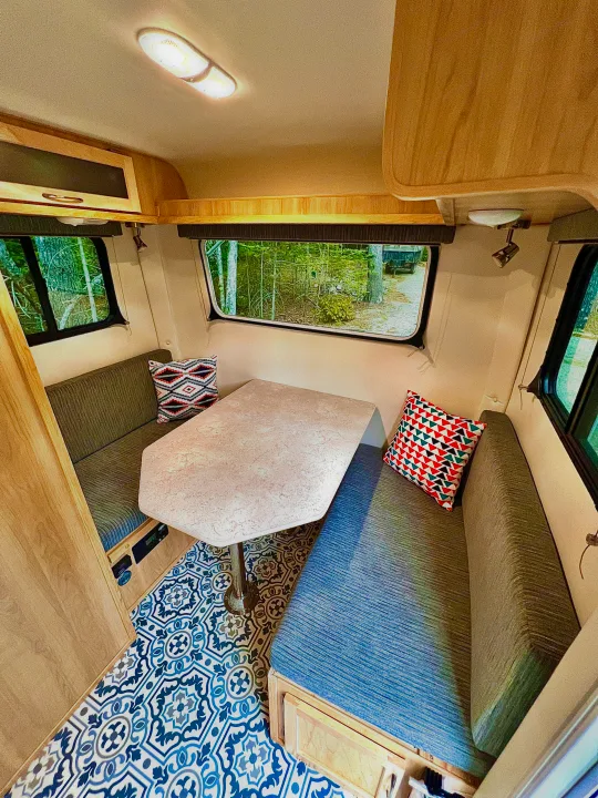 Cozy rv rental interior with a bright dinette, patterned blue floor, wood accents, and scenic forest views.. Escape Trailer Escape Trailer Trailer 2022