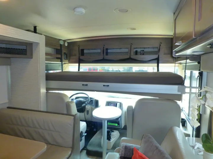 RV rental interior: overhead bunk, driver's cockpit, dinette, and ample storage. Your mobile adventure home.. Winnebago Vista 2020