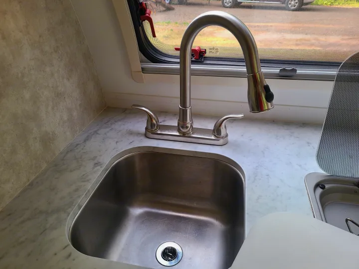 RV rental kitchen: Stainless steel sink, pull-down faucet, marble counter, and window view showing the outdoors.. Xtreme Outdoors Little Guy 2019