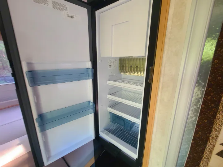 Interior view of a clean, empty RV rental refrigerator, featuring shelves & door bins, ready for your adventure.. Xtreme Outdoors Little Guy 2019