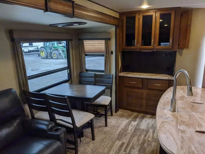 RV rental interior with dining area, kitchen, and a view of a tractor outside.. Grand Design Reflection 2018