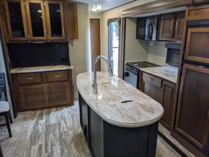 Spacious RV rental interior featuring a modern kitchen with an island, dark wood cabinets, and full appliances.. Grand Design Reflection 2018