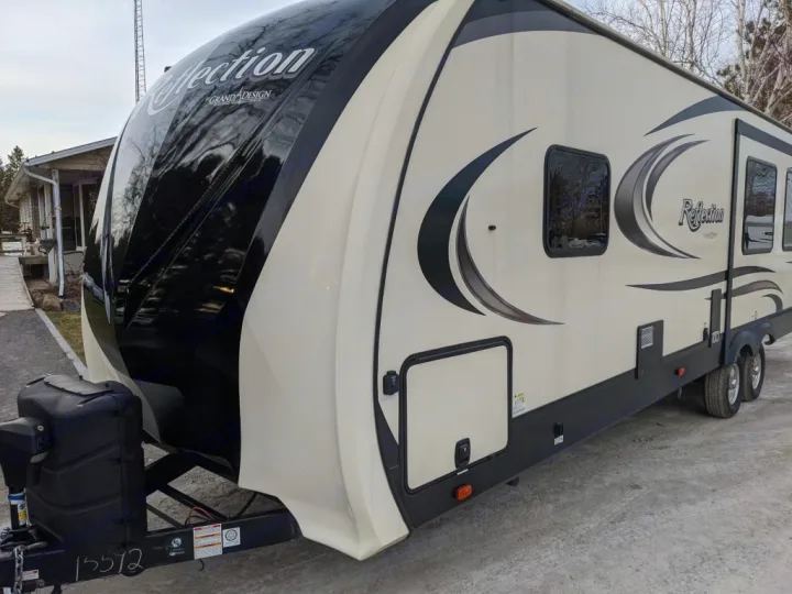 This beige Reflection Grand Design travel trailer is perfect for your next rv rental adventure, parked on a gravel lot.. Grand Design Reflection 2018