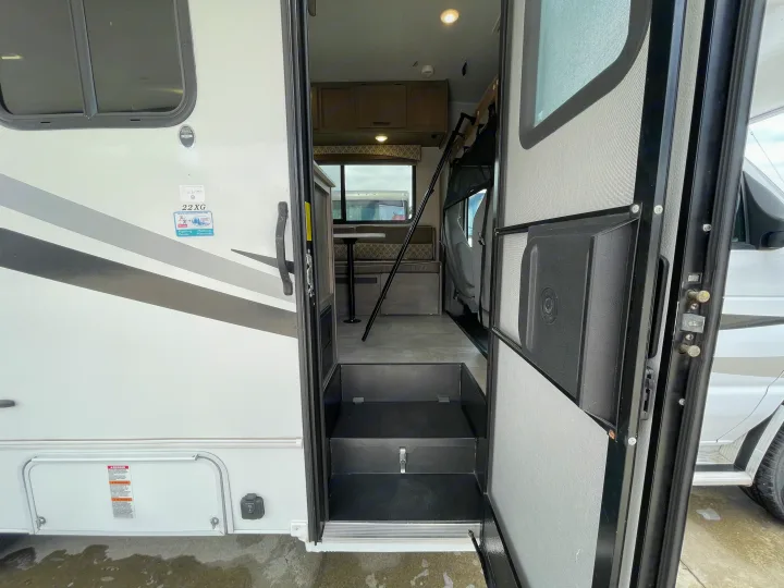 RV rental entrance with open screen door and steps. Interior view shows dinette, cabinets, and bunk. Ready for adventure!. Coachmen Freelander 2021