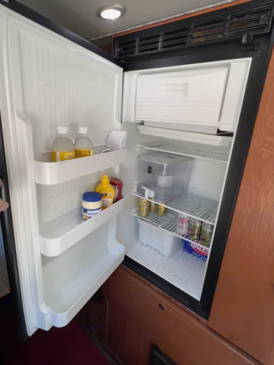 Open RV rental refrigerator showing drinks, condiments, and freezer. Stocked for your adventure!. Roadtrek Simplicity SRT 2019