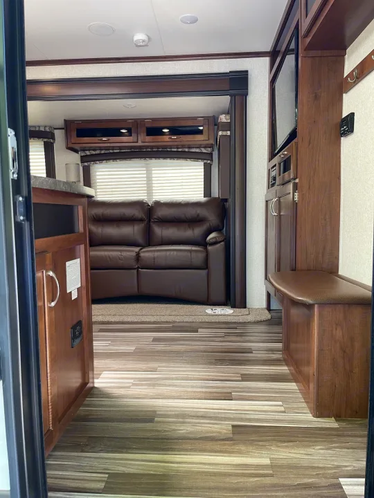 Modern RV rental living area: brown leather couch, entertainment center, and built-in bench seating.. Jayco Jay Flight 2017