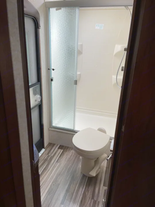 Inside an RV rental, a compact bathroom features a toilet and a shower with frosted glass.. Jayco Jay Flight 2017