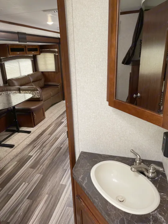 RV rental interior: view of bathroom sink, and living area with dining table and brown sofa.. Jayco Jay Flight 2017