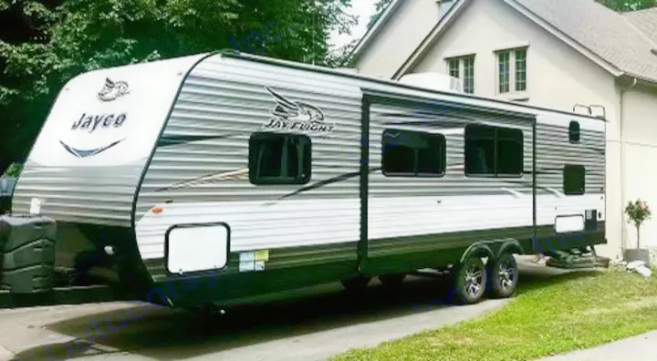 This grey and white Jayco Jay Flight travel trailer, an excellent RV rental option, is parked on a driveway by a house.. Jayco Jay Flight 2017