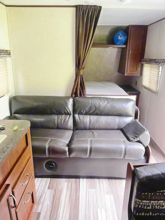 Compact RV rental interior featuring a comfy leather sofa, bed, and kitchenette.. Jayco Jay Flight 2017
