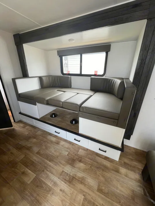 Spacious RV rental interior featuring a gray dinette, white table with cupholders, and wood-look flooring.. Hideout 181BH 2023