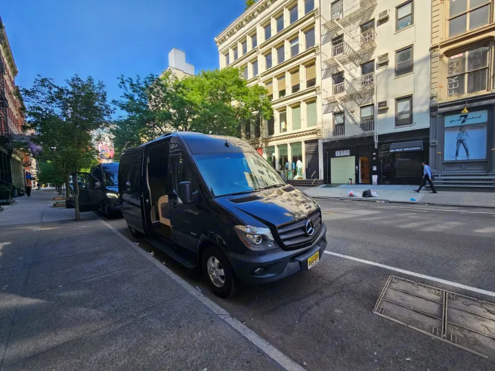 Black Mercedes Sprinter van on a sunny city street, ideal for group travel or as a spacious alternative for an rv rental experience.. Mercedes-Benz Sprinter 2016