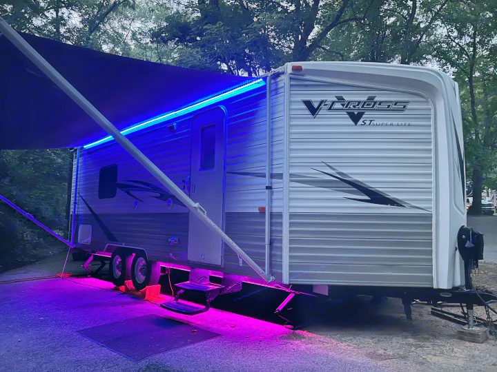 An RV rental at a campsite, brightly lit with blue awning and purple ground lights at night.. Forest River V-Cross ST Super Lite 2010