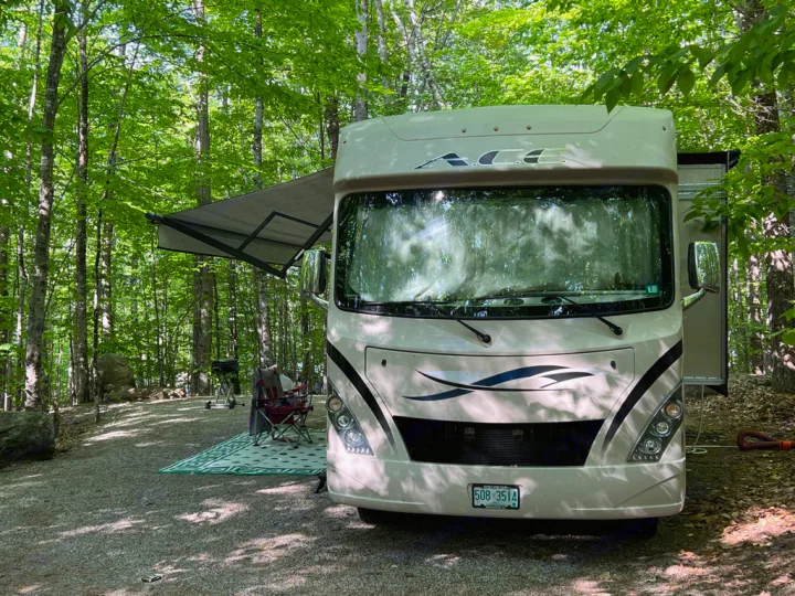 This RV rental is perfectly set up at a wooded campsite, with an extended awning, outdoor rug, chairs, and grill.. Thor Motor Coach A.C.E 2017