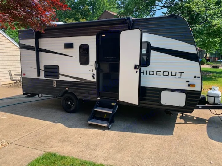 This Keystone Hideout travel trailer, perfect for an RV rental, features an open door with steps and is parked on concrete.. Keystone RV Hideout 2021