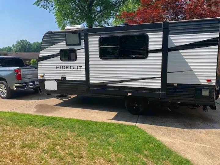 RV rental ready: A grey pickup truck is hitched to a white & black Hideout travel trailer on a sunny driveway.. Keystone RV Hideout 2021