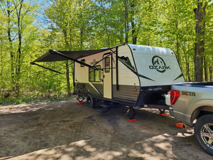 Perfect forest camping with an rv rental. Ozark travel trailer & truck in a sunny clearing, ready for adventure.. Ozark Ozark Trailer 2023