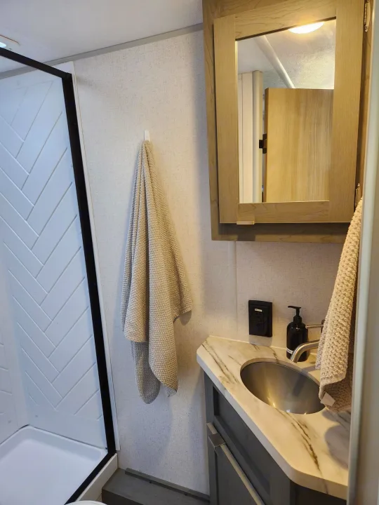 RV rental: Modern bathroom with marble-look sink, mirrored cabinet, folded towels, and herringbone shower.. Ozark Ozark Trailer 2023