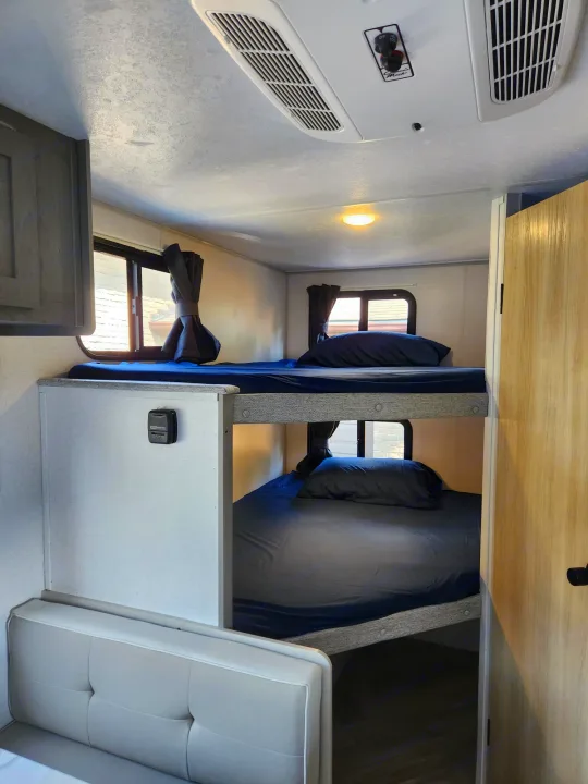 RV rental bunk beds, offering a compact sleeping area with AC and windows for travelers.. Ozark Ozark Trailer 2023