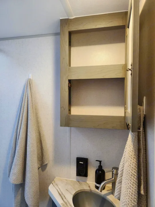 See inside an RV rental! Compact bathroom with open wall cabinet, sink, faucet, soap dispenser, and soft towels.. Ozark Ozark Trailer 2023