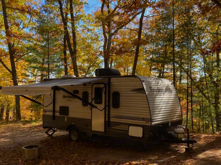 Enjoy an RV rental: a Springdale Mini trailer nestled in a scenic autumn campsite with fall foliage and clear skies.. Keystone RV Springdale 2019