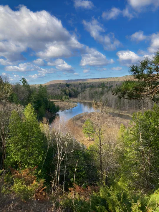 Scenic river valley with forested hills under a blue sky. Perfect for an RV rental outdoor adventure.. Keystone RV Springdale 2019