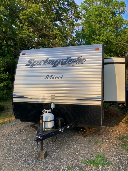 White Springdale Mini RV travel trailer parked on gravel, perfect for your next rv rental getaway.. Keystone RV Springdale 2019