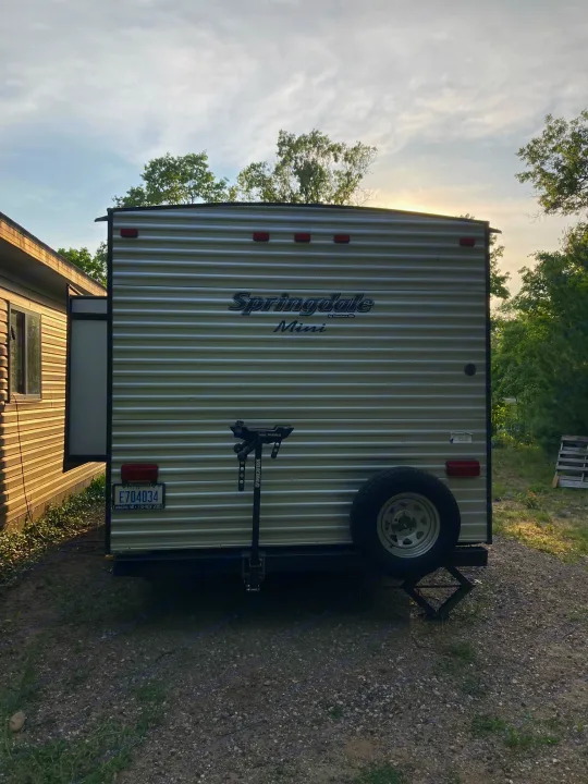 Rear view of a Springdale Mini travel trailer, featuring a spare tire & bike rack. Ideal for an rv rental.. Keystone RV Springdale 2019
