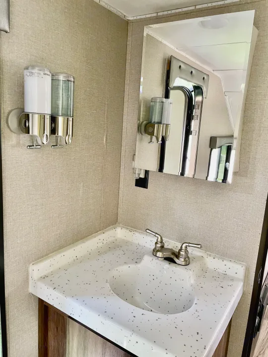 Compact RV bathroom sink area: modern vanity, faucet, and wall-mounted dispensers for comfort in your rv rental.. Travel Lite Aura 2019