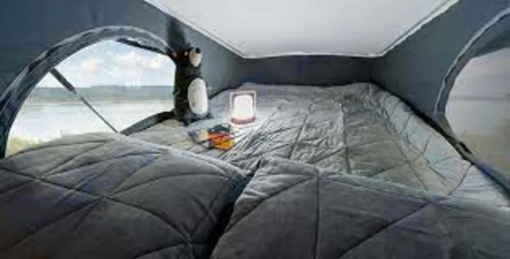 Inside an RV rental pop-top, a plush gray bed faces a stunning lake view. Perfect for comfortable camper travel & camping.. Winnebago Solis 2021