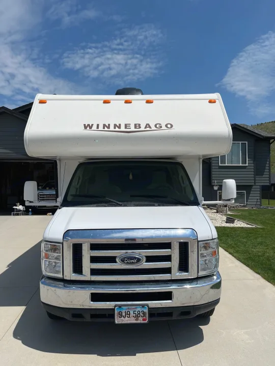 This clean white Ford Winnebago RV rental is ready for its next adventure, parked in a sunny home driveway.. Winnebago Minnie Winnie 2014