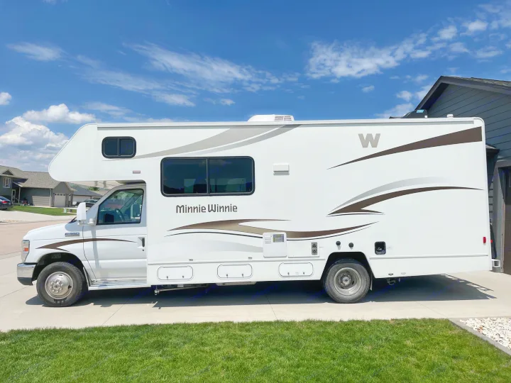 White Minnie Winnie RV parked on a driveway, a recreational vehicle ready for your next rv rental trip.. Winnebago Minnie Winnie 2014