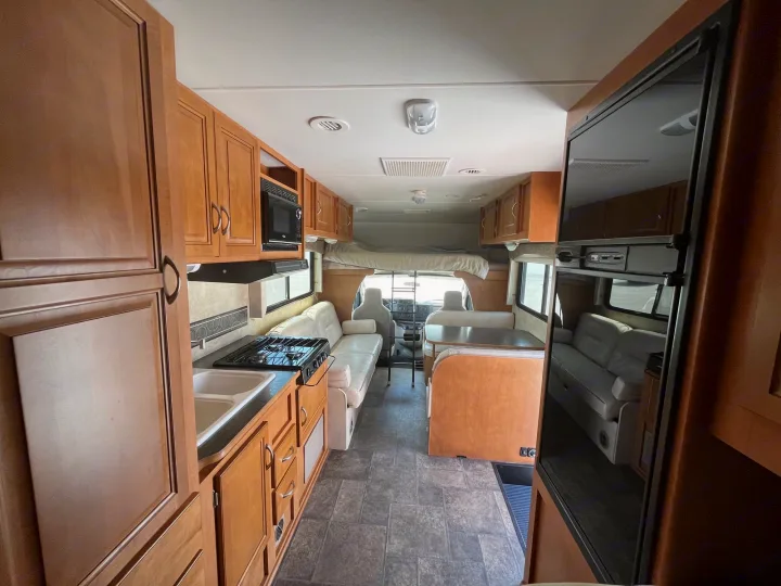 Spacious RV rental interior with kitchen, dining, and living areas visible, offering a clear view of its comfortable layout.. Winnebago Minnie Winnie 2014