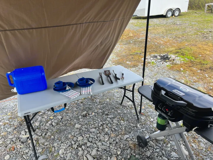 RV rental outdoor kitchen setup: portable grill, table, water jug & dishes under awning. Perfect for camping!. Toyota Tacoma 2012