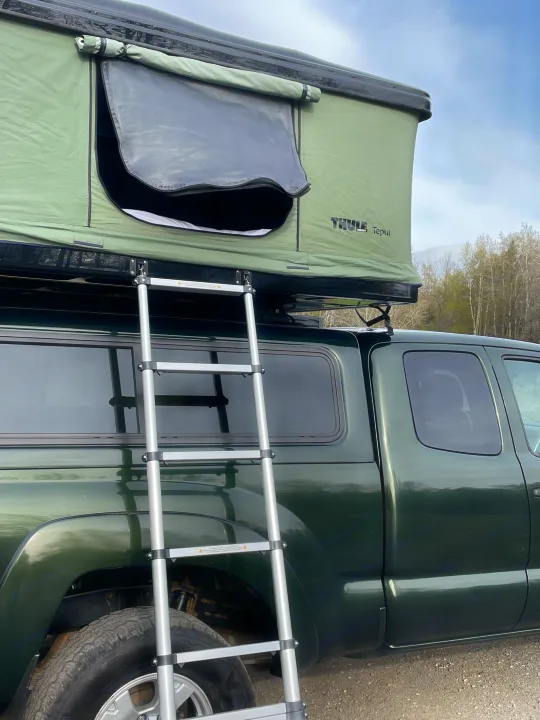 Green pickup truck with a Thule Tepui rooftop tent and ladder, offering a unique RV rental camping experience.. Toyota Tacoma 2012